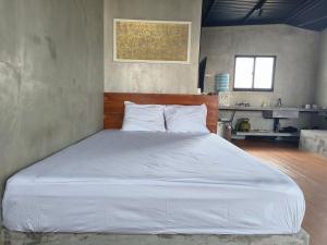 Una cama blanca grande en una habitación con cocina. en Industrial nia room, en Kerobokan