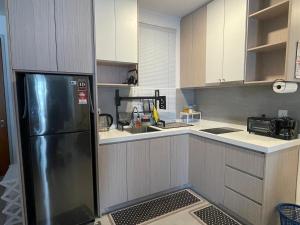 a kitchen with a black refrigerator and white cabinets at RaaNest, Sunsuria Forum in Shah Alam