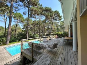 eine Terrasse mit einem Tisch, Stühlen und einem Pool in der Unterkunft Villa 10pers avec piscine privée in Lacanau