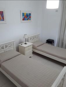 ein Schlafzimmer mit 2 Betten und eine Kommode mit einer Lampe in der Unterkunft Dos Nogales 26 in Villa Carlos Paz