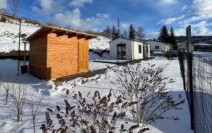 耶塞尼克Domeček Jasná的雪中带围栏的小木屋