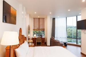 a bedroom with a bed and a desk and a room withwindows at Sài Gòn Heat Hotel in Ho Chi Minh City
