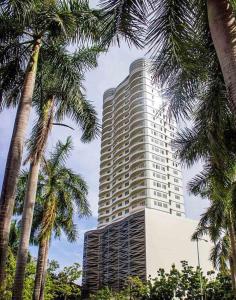 een hoog gebouw met palmbomen ervoor bij Modern Cozy with Netflix Condo Unit in Calyx Cebu Ayala in Cebu City