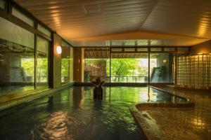 a person standing in a swimming pool in a building at Yamagataya in Gero