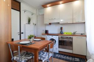 cocina con mesa de madera con sillas y lavadora en Vista Lago-Appartamento Giardino dell'Eden, en Ghirla 22 fotos más
