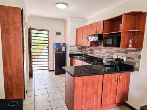 a kitchen with wooden cabinets and a black counter top at MPASSI Properties - Hatfiled, Pretoria in Pretoria