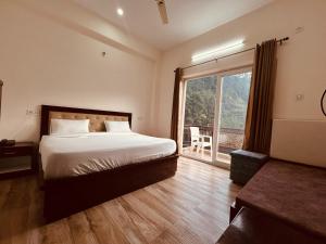 a bedroom with a bed and a large window at Hotel Anantam Residency in Uttarkāshi