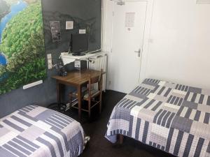 a room with two beds and a desk with a computer at Hôtel Le Rider in Bort-les-Orgues