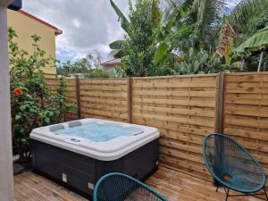 una vasca idromassaggio in un cortile con 2 sedie e una recinzione di La suite aux hibiscus a Le Lamentin