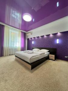 una camera da letto con un letto grande con pareti viola di ApartPoltava Неповторні апартаменти в ЦЕНТРІ Полтави КОРПУСНИЙ ПАРК a Poltava