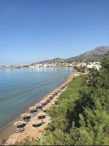 a beach with chairs and umbrellas and the water at Luxury Apartment in Makry Gialos in Ierápetra