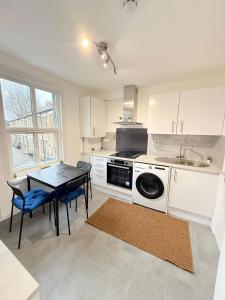 a kitchen with a table and a stove and a sink at Finsbury Park Rooms in London