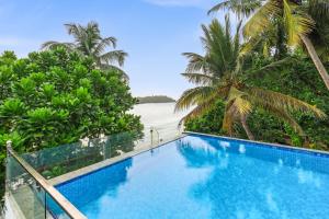 ベントータにあるHotel Nilwalaの海とヤシの木の景色を望むスイミングプール