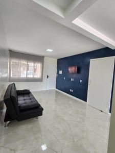 a living room with a black leather couch in a room at Apartamento-3 pé na areia, churrasqueira, acesso a lagoa, vista para rio, Torres e serra gaúcha in Passo de Torres