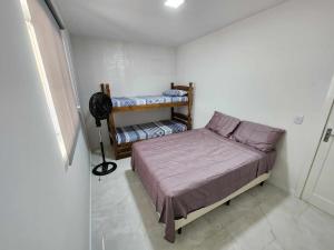 a small bedroom with a bed and two bunk beds at Apartamento-3 pé na areia, churrasqueira, acesso a lagoa, vista para rio, Torres e serra gaúcha in Passo de Torres