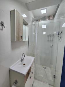 a white bathroom with a shower and a sink at Apartamento-3 pé na areia, churrasqueira, acesso a lagoa, vista para rio, Torres e serra gaúcha in Passo de Torres +23 photos