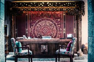 two chairs in front of a stage with a tapestry at Arro Khampa By Zinc Journey Shangri-la in Shangri-La