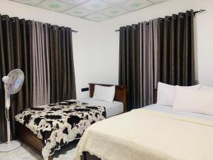 two beds in a room with curtains and a fan at Nethuli Inn Ella in Ella