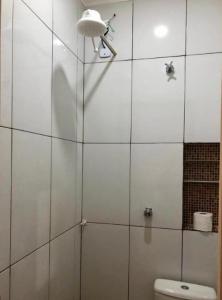 a white tiled bathroom with a shower and a toilet at Pousada MC in Aparecida +86 photos