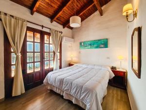 a bedroom with a large white bed and windows at Hotel Marqués del Lago in Villa Carlos Paz