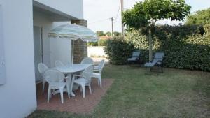 a patio with a table and chairs and an umbrella at Superbe Logement à 200 m de la Plage ! T4 Coquillages in Saint-Pierre-dʼOléron