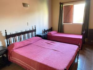 two beds in a room with pink covers on them at Departamentos LOS CEDROS in Mina Clavero