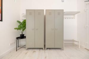 three white lockers in a white room with a potted plant at Great 2-room apartment in Mitte in Berlin