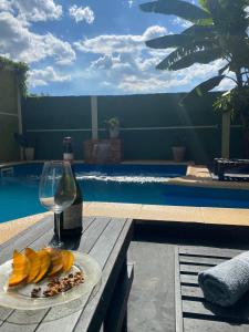 a glass of wine and a plate of fruit on a table by a pool at Rincón del parana in Puerto Iguazú