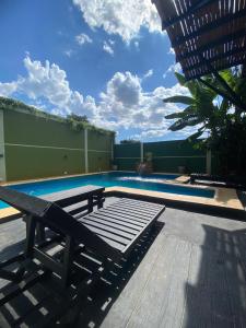 a swimming pool with a wooden deck and a bench at Rincón del parana in Puerto Iguazú