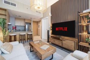 un soggiorno con TV e cucina di 1BR The Monarch Suite by Blue Cloud Holidays a Sharjah