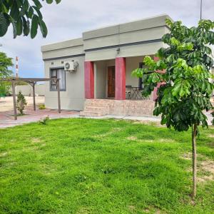 a small building with a green lawn in front of it at AYA Apartment in Maun