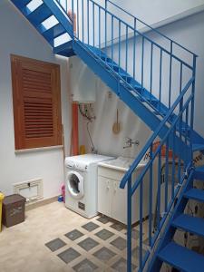 a laundry room with a washer and a blue staircase at Appartamento Marco a pochi passi dal mare S.Vito in San Vito lo Capo