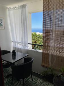 a table and chairs in a room with a window at Appartement cosy avec garage in Le Tampon
