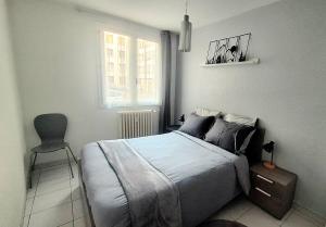 a bedroom with a bed with a chair and a window at Appartement central avec parking in Carcassone