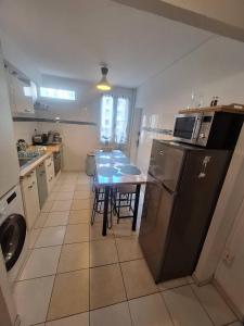 a kitchen with a table and a table and a refrigerator at Appartement central avec parking in Carcassone