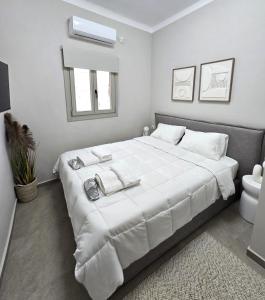 een witte slaapkamer met een groot bed met handdoeken erop bij Urban Nest Kalymnos in Kalymnos