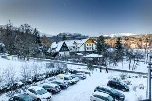 a group of cars parked in a parking lot covered in snow at Karkonoskie Widoki Apartamenty in Karpacz +65 photos