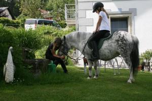 Una ragazza che cavalca un cavallo accanto a una donna di Ferienbauernhof Rosenberger a Hauzenberg
