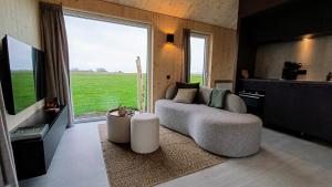 a living room with a couch and a large window at Boerenerf Lodge - Erf 1 in Kampen