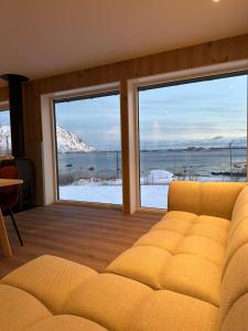 a living room with a couch and two large windows at Lofoten Seaview apartment in Vestvågøya