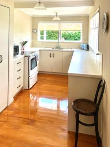 a kitchen with white cabinets and a wooden floor at Graceful Character Cottage In The Leafy Avenues in Tauranga