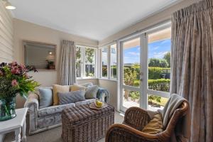 a living room with a couch and a large window at Graceful Character Cottage In The Leafy Avenues in Tauranga