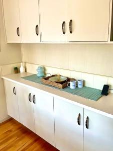 a kitchen counter with white cabinets and a basket on it at Graceful Character Cottage In The Leafy Avenues in Tauranga +21 photos