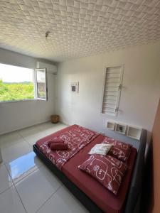 1 dormitorio con 1 cama roja en una habitación con ventana en Locations Villa Saint-Francois, en Saint-François