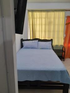 a bedroom with a bed with blue sheets and a window at Posada for Living in San Andrés