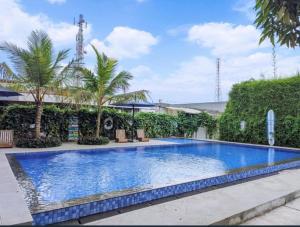a large blue swimming pool with palm trees and bushes at Terra Cassa in Semarang