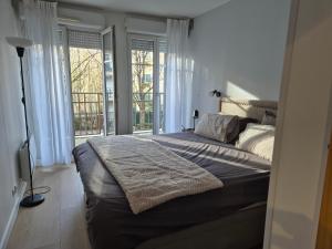 een slaapkamer met een groot bed in een kamer met ramen bij Appartement cosy près du RER in Chessy