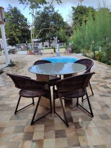 累西腓Refúgio Completo com Piscina em Aldeia dos Cãmaras的一个带游泳池的庭院里的玻璃桌子和椅子
