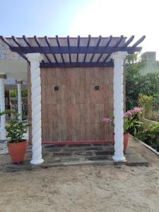 累西腓Refúgio Completo com Piscina em Aldeia dos Cãmaras的凉棚下面有两株盆栽植物 更多12张照片