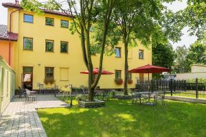 un bâtiment jaune avec des tables et des parasols dans une cour dans l'établissement HOTEL I RESTAURACJA BROCHÓW, à Wrocław